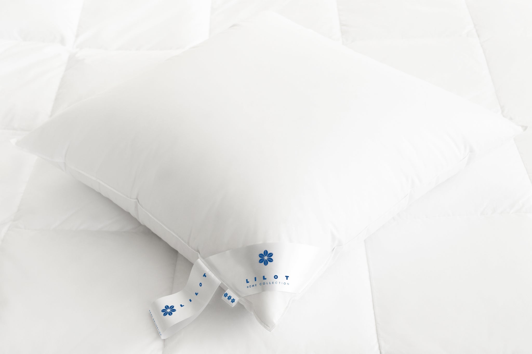 An Aurora Lilot Firm Pillow resting on a plush down duvet.