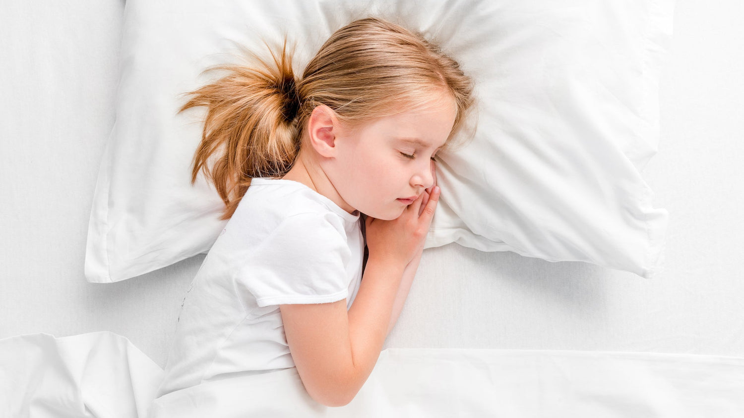 A child peacefully sleeping in bed with an Aurora Lilot Kids Balanced Pillow, highlighting comfort and tranquility.