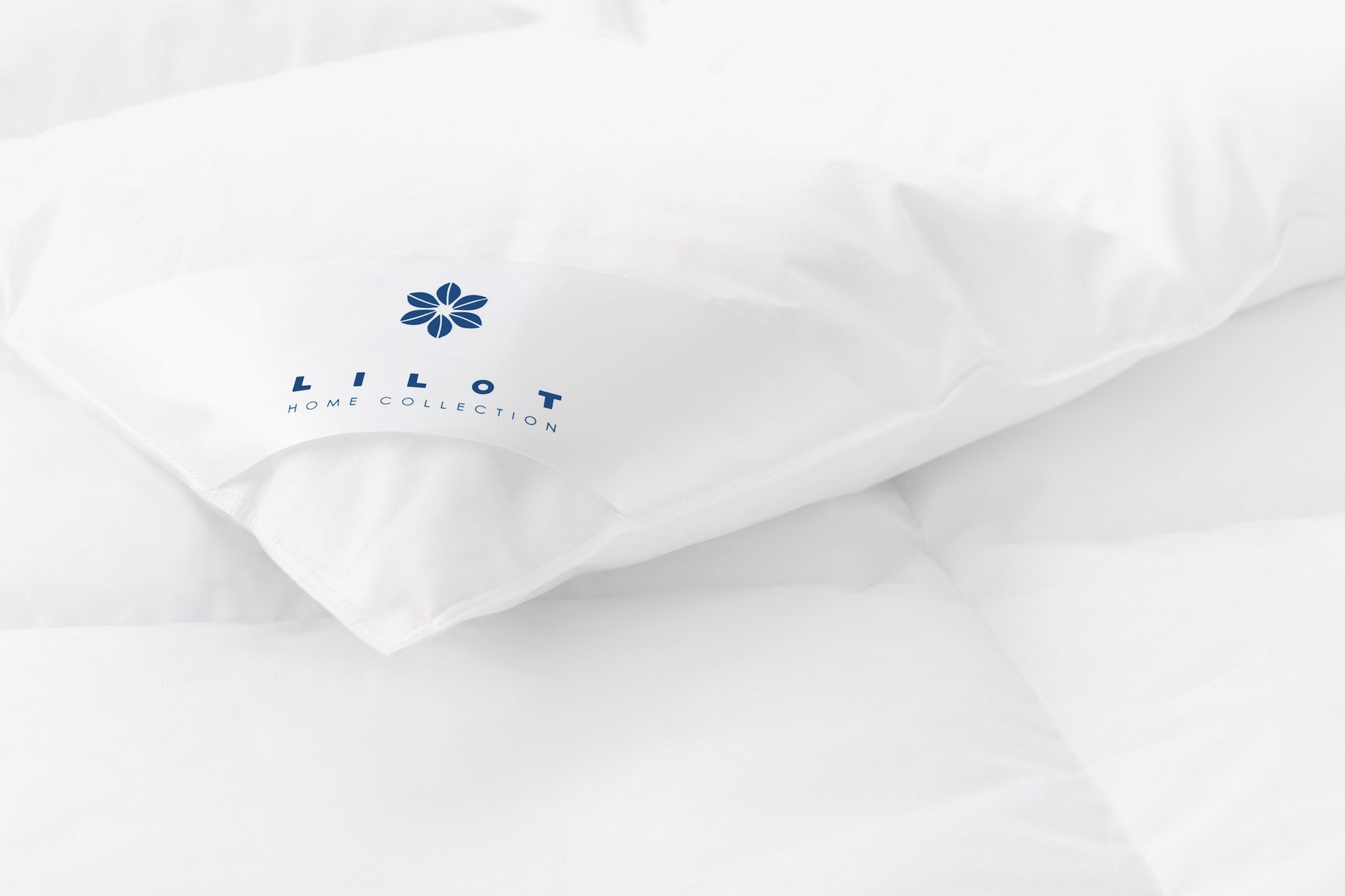 Close-up of the corner of the Lilot Summer (light-warm, light-weight) Goose Down Duvet, featuring a brand label with a navy-blue logo sign.