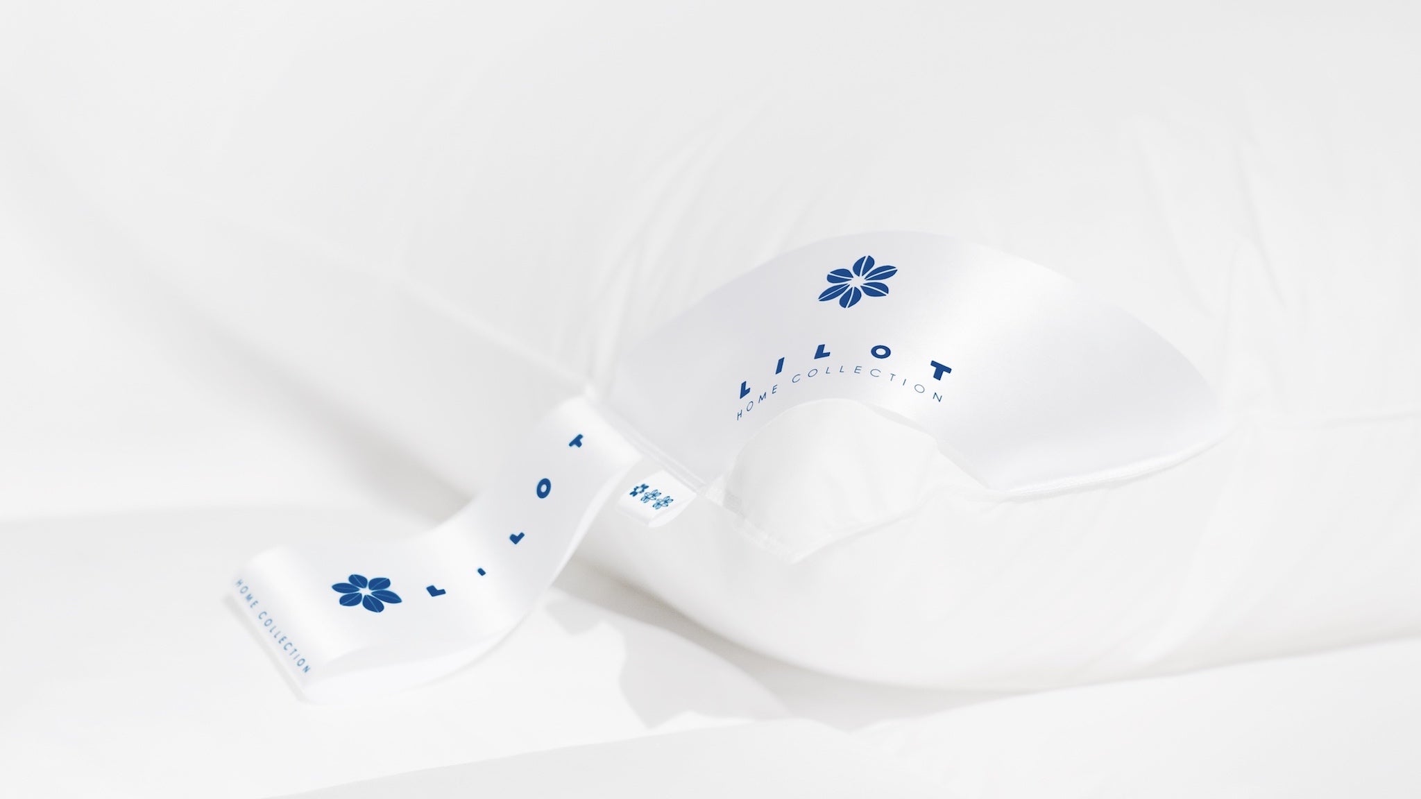 Close-up of a luxurious Aurora Lilot pillow with a white 'Lilot Home Collection' tag featuring a blue logo.