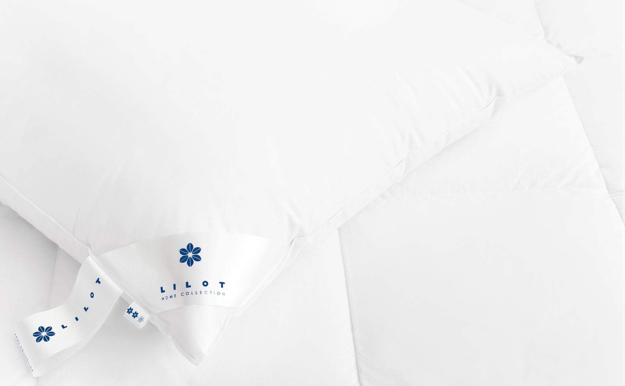 Luxurious Aurora Lilot Down Pillow atop a duvet.