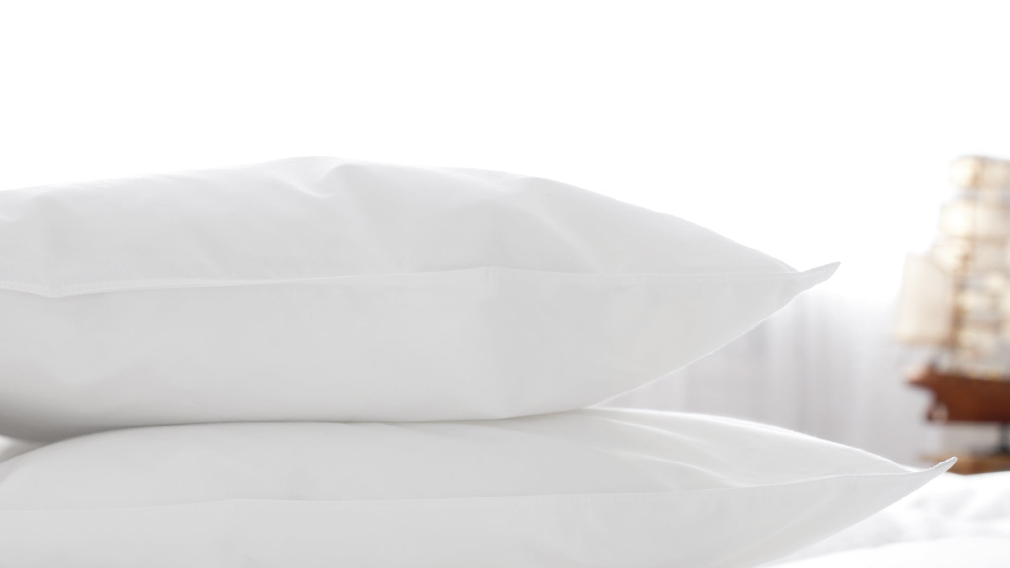 Soft and fluffy Aurora Lilot pillows in various sizes are arranged on a bed to create a comfortable sleep setting.