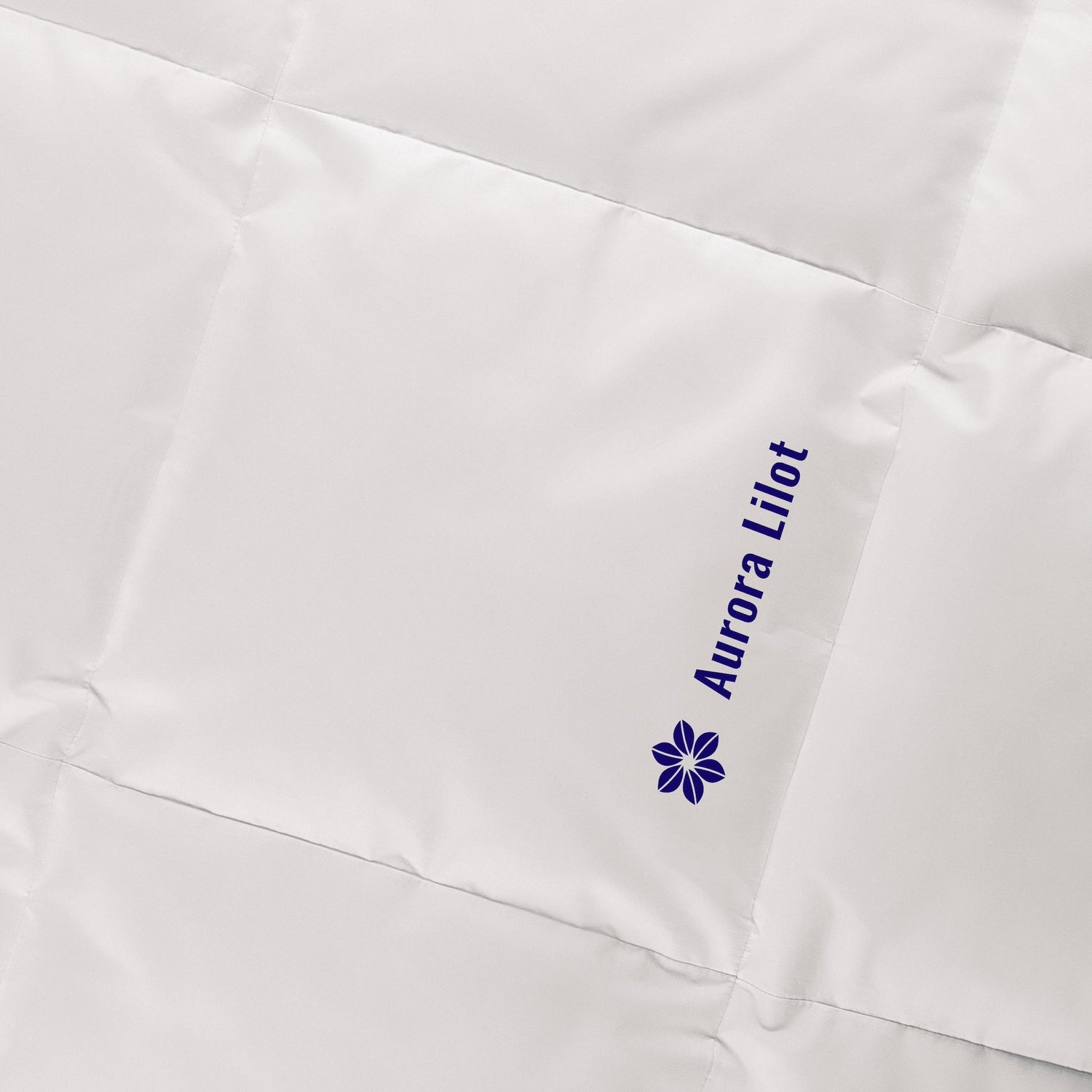 The Aurora Lilot Duvet with dark blue logo exudes elegance and charm, perfect for a lavish bedroom setting.