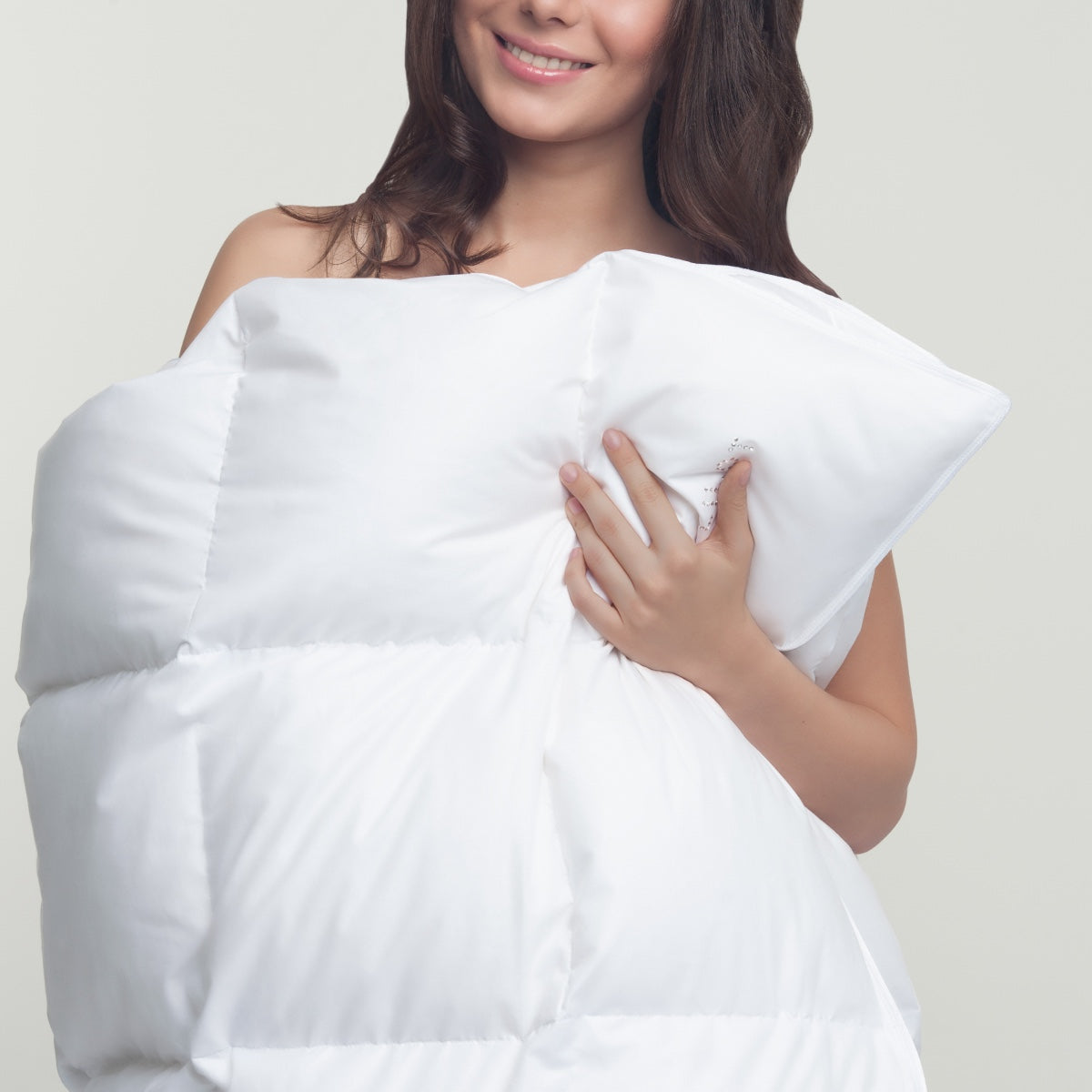 The exquisite Aurora Lilot duvet is elegantly cradled in a graceful hand.